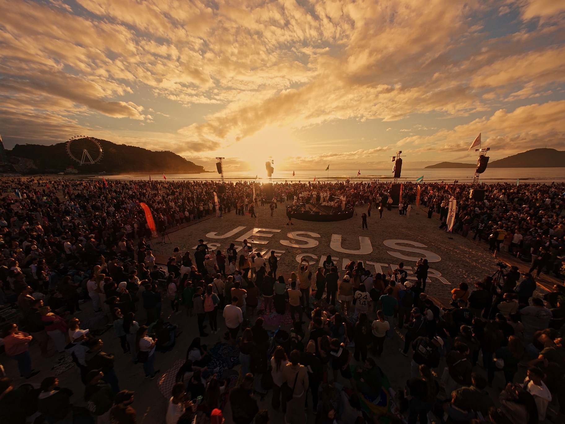 Amanhecer na praia com letreiro Jesus is the Center
