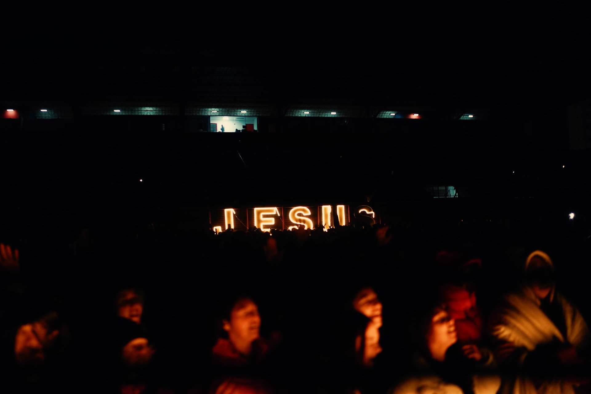 Letreiro Jesus iluminado em meio à multidão